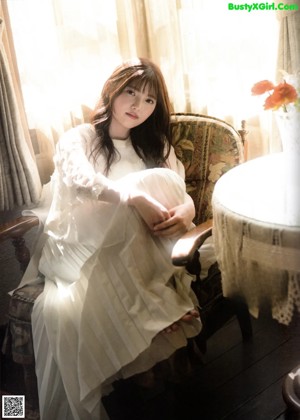 A woman in a white dress standing in a room.