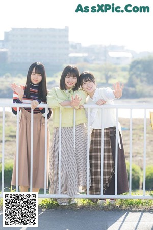 A group of young women sitting on top of a lush green field.