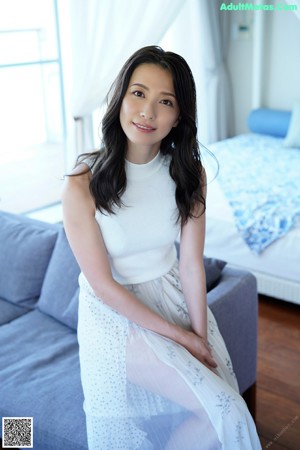 A naked woman sitting on a bed in a bedroom.