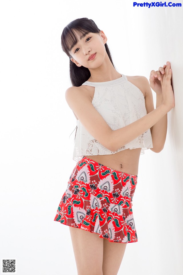 A woman in a white top and red skirt posing for a picture.