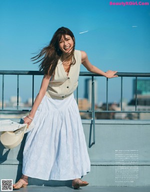 A woman in a green dress is posing on a balcony.