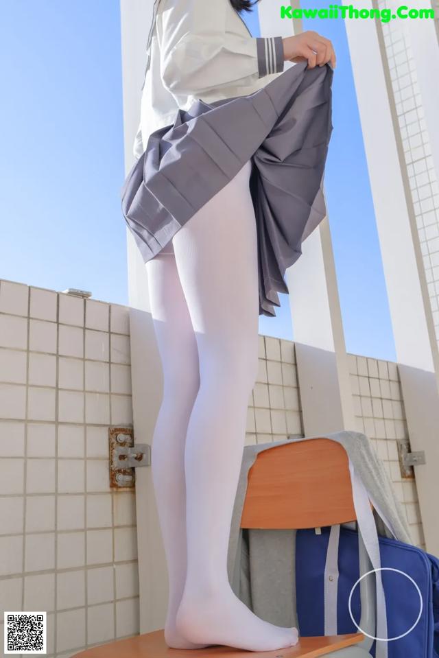 A woman in white tights is standing on a chair.