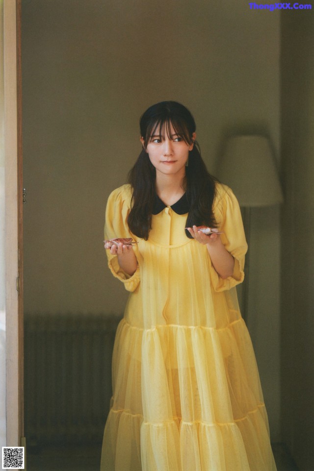 A woman in a yellow dress standing in front of a door.