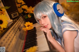 A woman with blue hair sitting on the floor holding a sunflower.