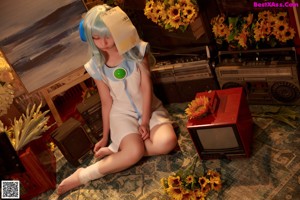 A woman with blue hair sitting on the floor holding a sunflower.