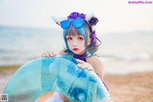 A woman in a purple bikini sitting on the beach.