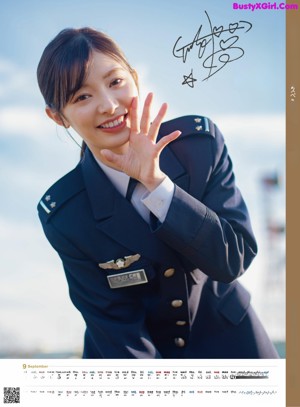 A woman in a military uniform waving at the camera.