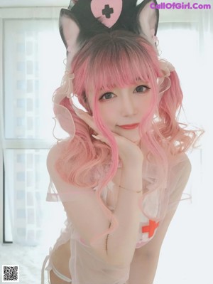 A woman with pink hair wearing a nurse outfit.