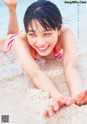 A woman in a blue bikini laying on the beach.