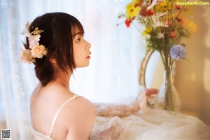 A woman in a white dress looking out of a window.