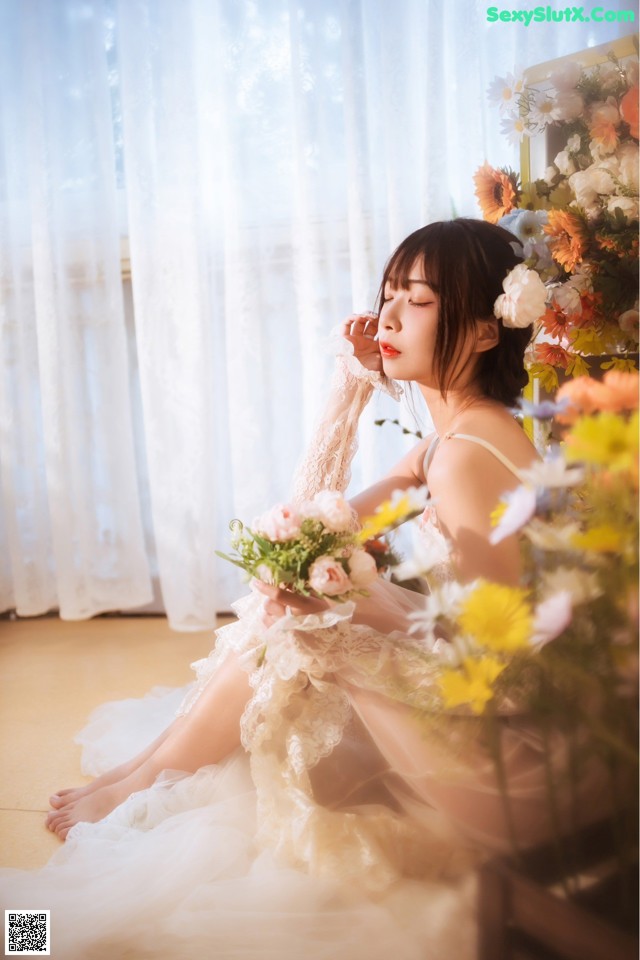 A woman sitting on the floor holding a bouquet of flowers.