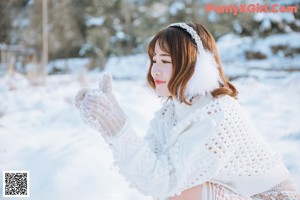 A woman in a white dress and a red hat in the snow.