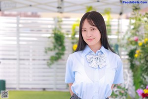 A woman in a blue shirt and plaid skirt posing for a picture.