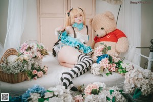 A woman sitting on top of a bed next to a basket of flowers.