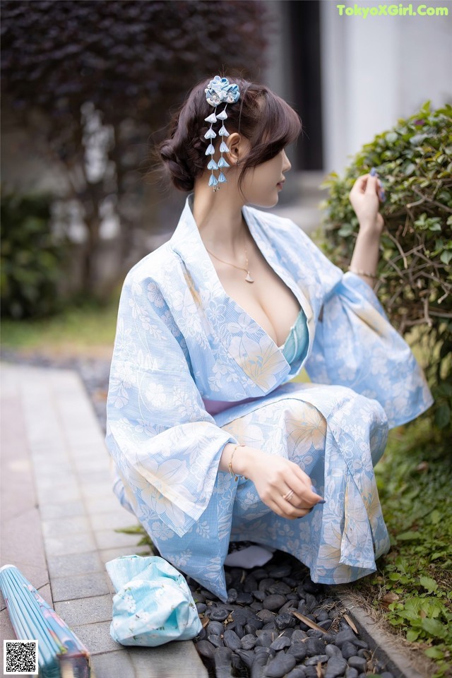 A woman in a blue kimono sitting on the ground.