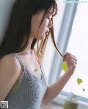 A woman sitting on a window sill next to a bottle of water.