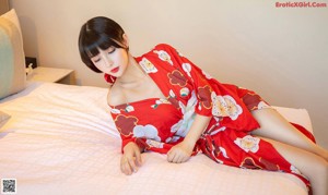 A woman in a red kimono sitting on a table.