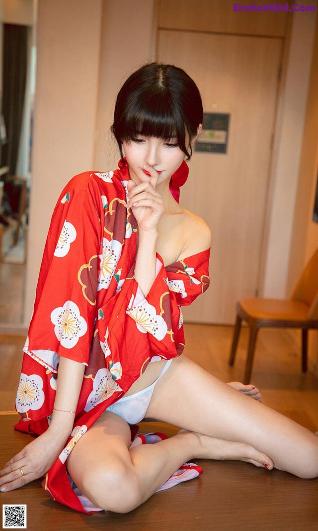 A woman in a red kimono sitting on the floor.