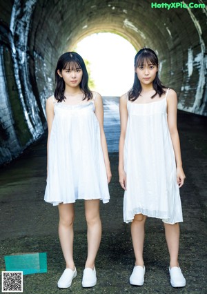 Two young women sitting next to each other on a bed.