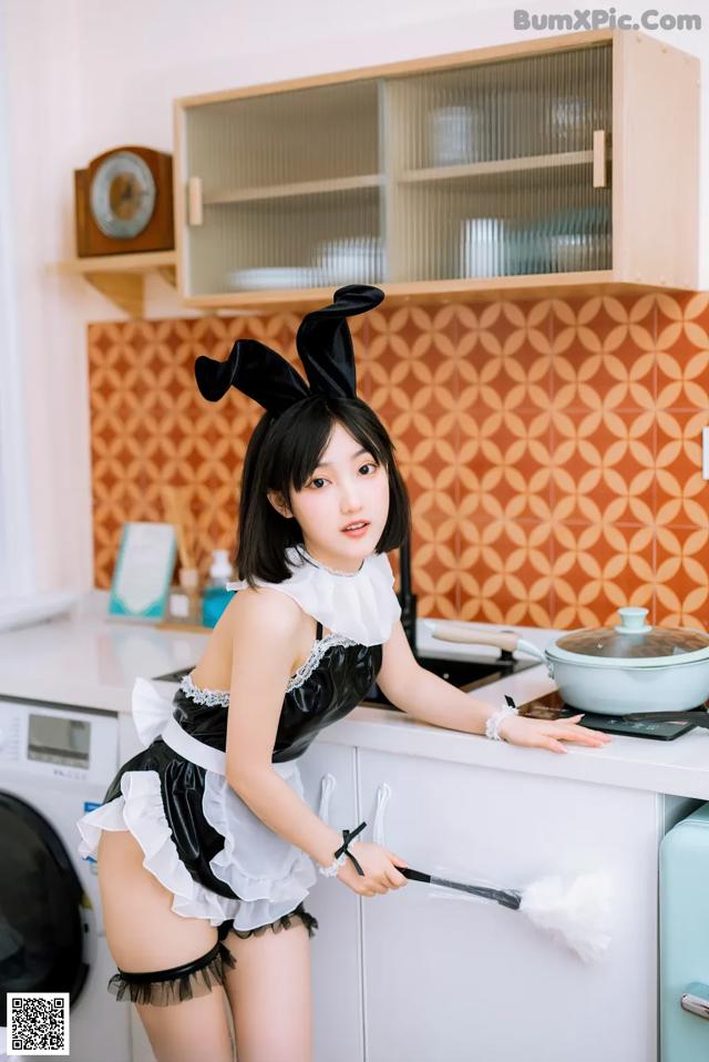 A woman in a bunny costume cleaning a kitchen counter.