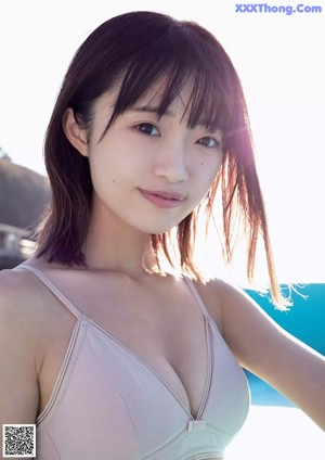 A woman in a white sweater is standing on the beach.