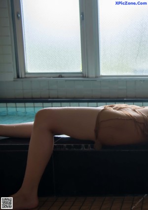 A woman in a striped bathing suit standing next to a shower.