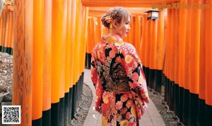 A woman in a kimono standing in front of a pagoda.