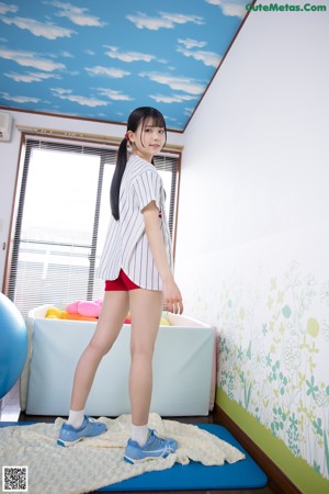 A young woman is posing on a red ball.