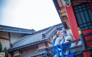 A woman in a blue and white outfit sitting on a bench.