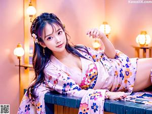 A woman in a white and pink kimono posing for a picture.