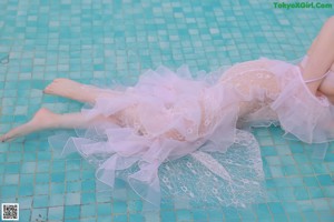 A woman in a white lingerie sitting in a pool.