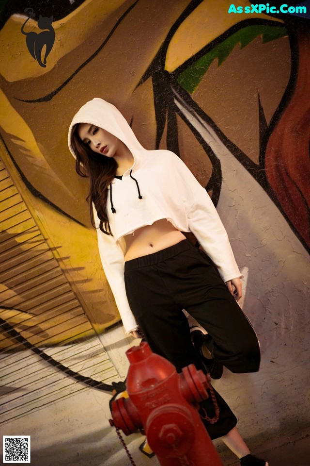 A woman in a white hoodie standing next to a red fire hydrant.