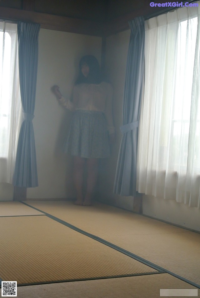 A woman standing in front of a window in a room.