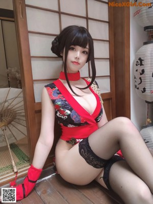 A woman in a red and black lingerie posing for the camera.