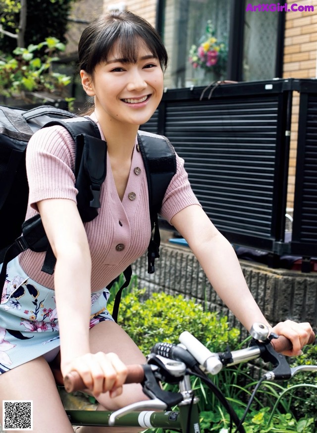 A woman riding a bike with a backpack on her back.