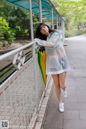 A woman in a white shirt and skirt holding an umbrella.