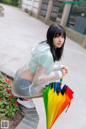 A woman sitting on a bench holding an umbrella.