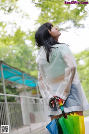 A woman in a white shirt and skirt holding an umbrella.