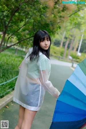 A woman in a white shirt and skirt holding an umbrella.