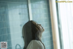 A woman in a black bikini leaning against a window.