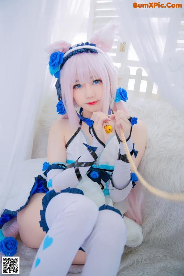 A woman in a blue and white outfit sitting on a bed.