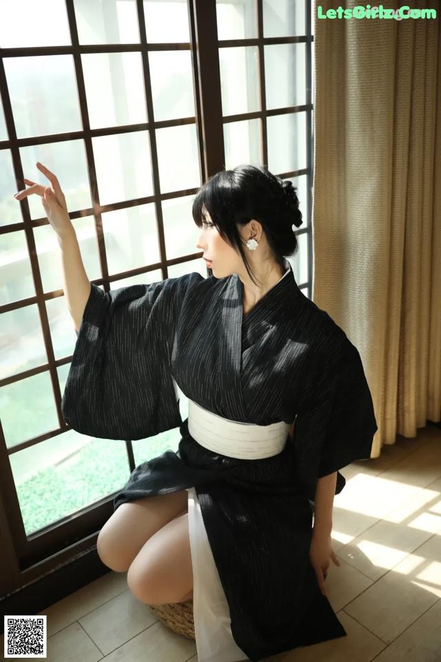 A woman in a black and white kimono sitting on the floor.